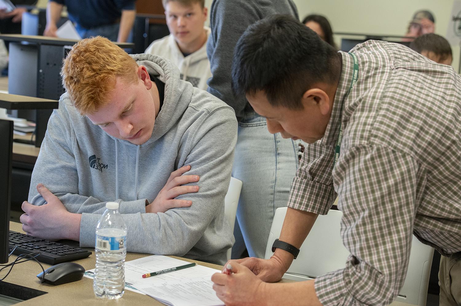 A professor leaning over to show a student something on a piece of paper